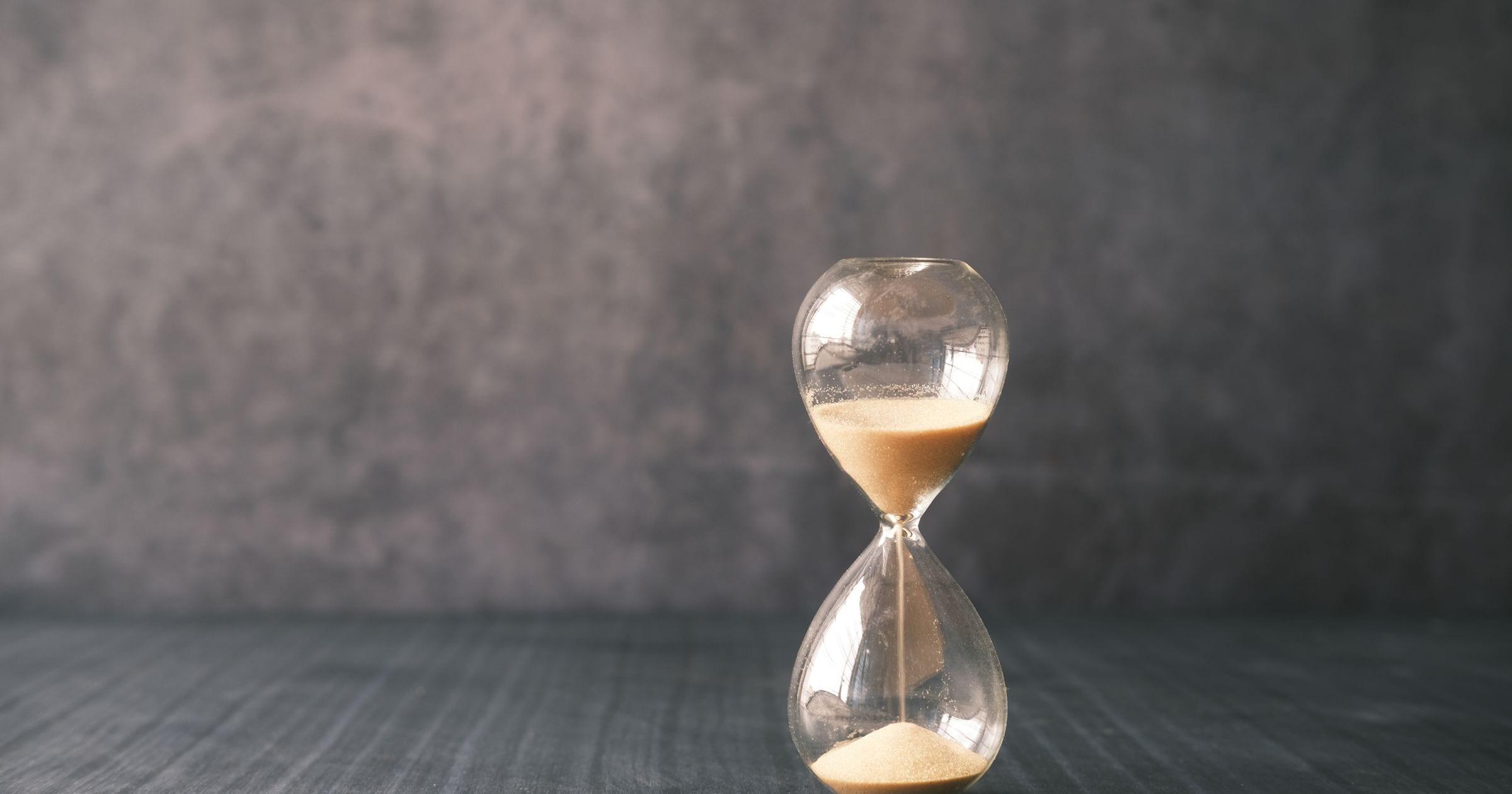 An hourglass with sand running through it, on a dark table